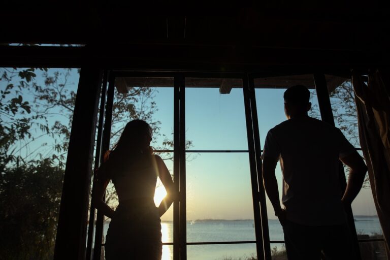 Couple standing apart by a window, reflecting on relationship difficulties