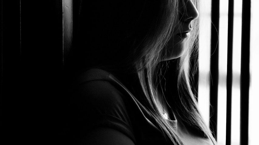Woman sitting alone in shadow, reflecting on grief and family changes after her mother’s death